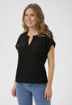 Black short-sleeve top with a v-neck and diamond pattern; made of lightweight material. Paired with blue denim jeans.