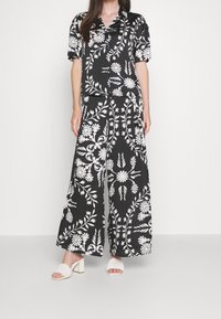 Dwuczęściowy zestaw w czarno-biały kwiatowy wzór, składający się z bluzki z krótkim rękawem i szerokich spodni, wykonany z gładkiej tkaniny o luźnym kroju.