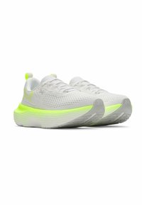 White athletic shoes with a textured upper, neon yellow accents on the sole, and a thick, cushioned midsole design.