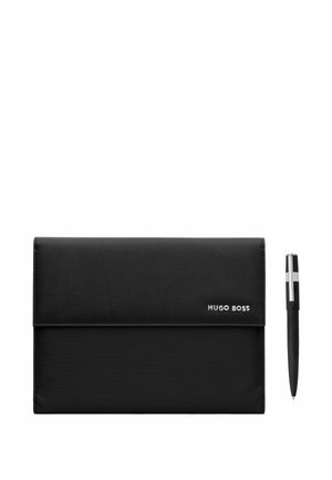 Porte-documents noir Hugo Boss avec une base texturée et un logo en métal, à côté d'un stylo noir avec clip argenté sur fond blanc.