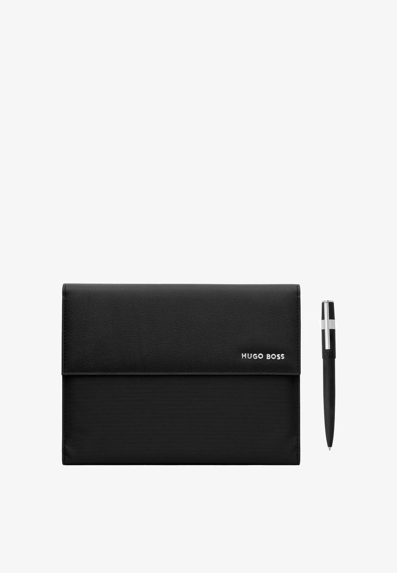 Porte-documents noir Hugo Boss avec une base texturée et un logo en métal, à côté d'un stylo noir avec clip argenté sur fond blanc.