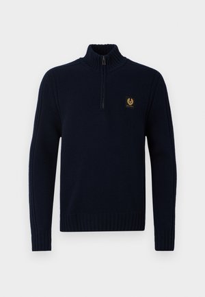 Pulover tricotat bleumarin cu guler înalt, fermoar pe jumătate și manșete nervurate. Prezintă un mic logo auriu pe piept. Textură netedă.
