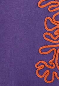 Textil violet cu o textură netedă, prezentând un design complex brodat în portocaliu, care seamănă cu linii fluide.