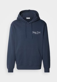Mørk marineblå hettegenser med en frontlomme, snorhette og hvit brodert tekst "New York" og "Calvin Klein Jeans" på brystet.