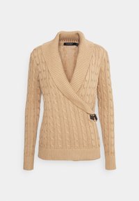 Beżowy sweter w splot kabel z kołnierzem szalowym, długimi rękawami i ukośnym zapięciem z przodu z ozdobną klamrą.