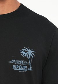 Čierne bavlnené tričko s grafikou svetlomodrých paliem a vĺn, pod ktorou je text "RIPCURL SURFING CO.".