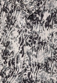 Camicetta a maniche corte in un motivo astratto nero, grigio e bianco. Presenta un colletto classico e bottoni neri lungo la parte anteriore.