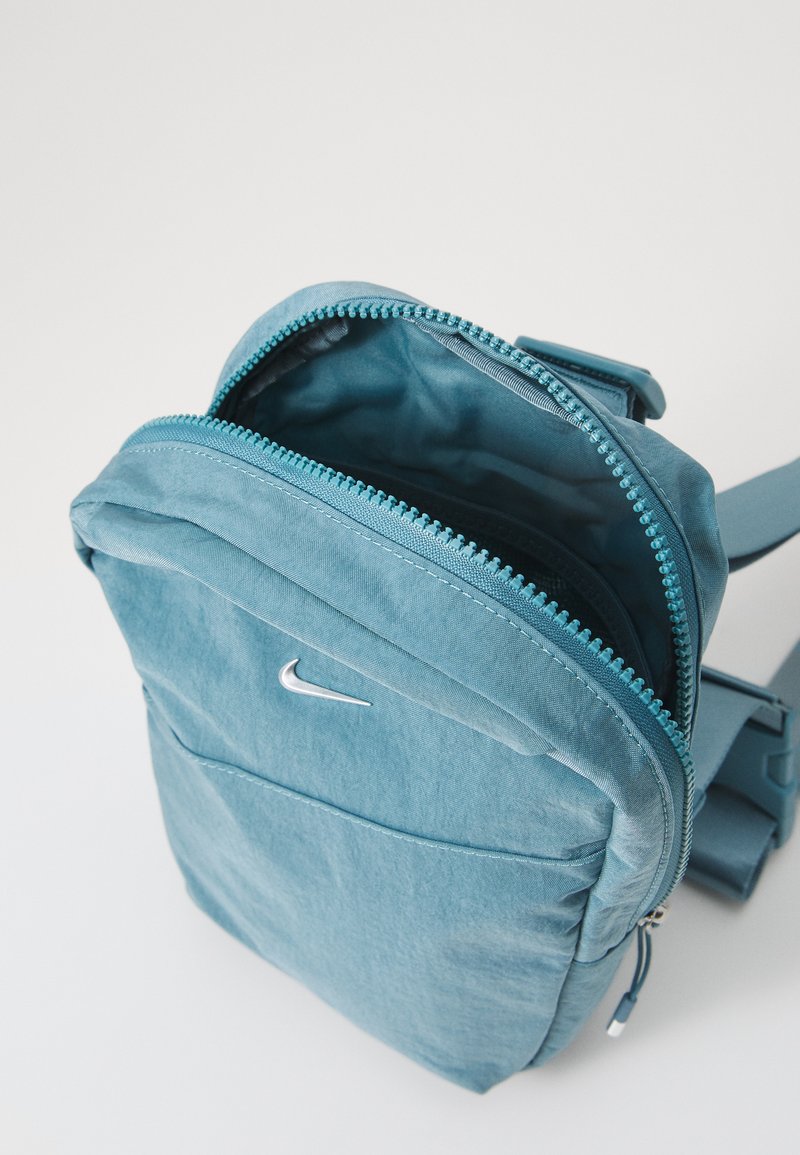Mochila Nike en tela azul claro, con cierre de cremallera, espalda acolchada y un pequeño logo plateado en la parte frontal.