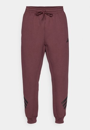 Pantalones jogger de color granate con cintura elástica, cordón ajustable, puños acanalados y logo negro de Adidas en el muslo izquierdo, con franjas cerca de los tobillos.