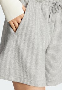 Ljusgrå shorts av strukturerat tyg, med sidfickor och resårmidja med dragsko. Diskret märkning synlig vid fållen.