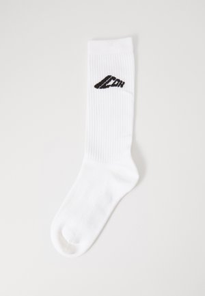 White ribbed knee-length sock featuring a black logo on the side, crafted from soft cotton blend material with a smooth texture.