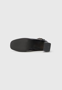 Stivale nero con tacco, realizzato in pelle liscia nella parte superiore, punta quadrata, tacco testurizzato e dettaglio metallico vicino alla caviglia.