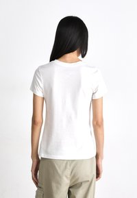Witte katoenen t-shirt met korte mouwen en een ronde halslijn, gezien vanuit de achterkant, met een gladde textuur en een minimalistisch ontwerp.