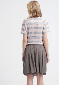 Top de manga corta a rayas en rosa y gris con tejido texturizado. Combinado con una falda plisada marrón-gris a la altura de la rodilla.