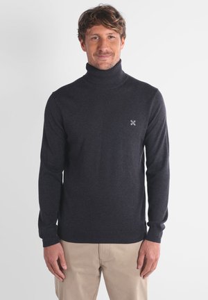 Pull à col roulé gris foncé en matière tricot douce, avec des manches longues et un petit logo sur la poitrine gauche.