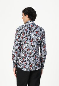 Menns langermet skjorte i lyseblått med blomsterdesign i rødt, svart og hvitt; har krage og buet søm.