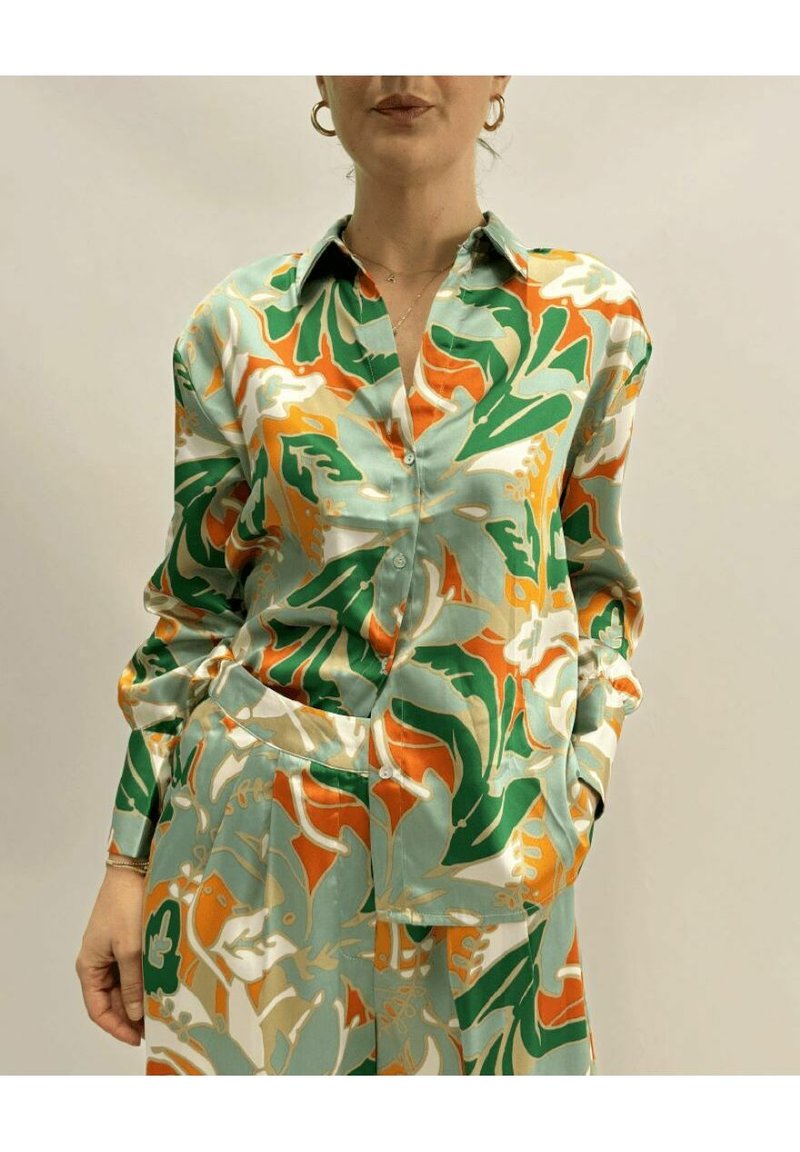 Camicia in satin verde, arancione e crema con motivo floreale; presenta un colletto, chiusura con bottoni e maniche lunghe con tasca.