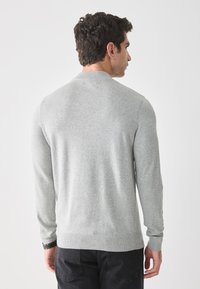 Helle graue Strickjacke mit langen Ärmeln, gerippten Bündchen und Saum. Glatte Textur und klassischer Rundhalsausschnitt.