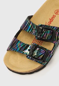 Πολύχρωμα σανδάλια με μαύρες και ιριδίζουσες ριγέ λουράκια, διαθέτουν δύο ρυθμιζόμενες μαύρες αγκράφες και ανοιχτό καφέ σουέτ πάτο.