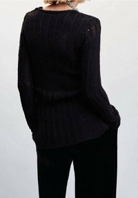 Czarny sweter z prążkowanej dzianiny z okrągłym dekoltem i długimi rękawami, charakteryzujący się dopasowanym krojem i teksturowanym detalem materiału.
