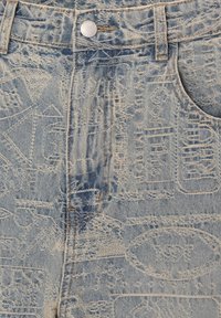 Jean en denim bleu clair avec logos vintage embossés et noms de marques, doté de poches avant, passants pour ceinture et d'une fermeture par bouton argenté.