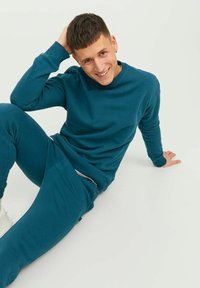 Teal sweatshirt en bijpassende joggers. De trui heeft een ronde hals en ribgebreide manchetten. De broek heeft zijzakken en een elastische tailleband.