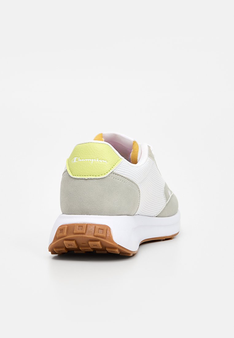 Zapatillas gris claro y blancas con una parte superior de malla texturizada, acentos de ante suave, una lengüeta verde en el talón y una suela de goma marrón.