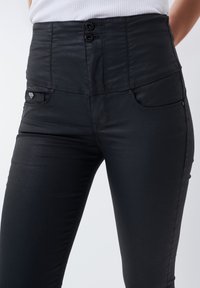 Hogewaist zwarte broek met een sluiting met twee knopen, voorzakken en een gladde stof, met subtiele stikdetails en een slim fit.