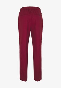 Pantalons bourgogne avec une taille élastique, deux poches arrière et une coupe droite. Tissu lisse avec une texture minimale.