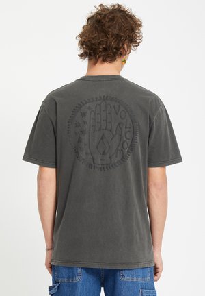 Grå bomulds t-shirt med et cirkulært, præget hånddesign og tekst på ryggen. Korte ærmer og en rund halsudskæring med en afslappet pasform.