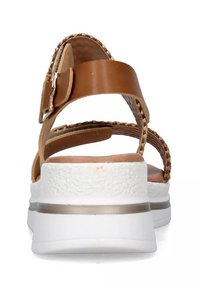 Sandali in finta pelle marrone con fasce intrecciate, suola bianca a piattaforma, accentuazione metallica e dettaglio testurizzato sul tacco. Chiusura con fibbia regolabile.