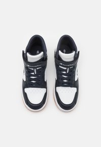 Wysokie trampki z granatowo-białej syntetycznej cholewki, wyściełanym kołnierzem, sznurówkami, perforowanym czubkiem oraz gumową podeszwą. Zawierają logo Champion.