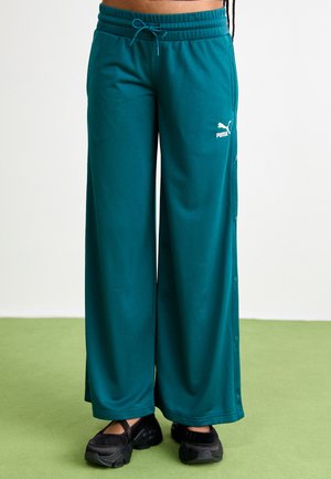 Tīrkšķi zaļas platās bikses no mīksta auduma, ar sašūtu jostu un spiedpogām gar sāniem. Puma logo baltā krāsā priekšpusē.