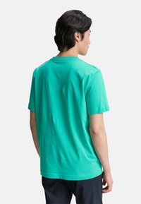 Turkise bomulds T-shirt med korte ærmer, rund hals og en afslappet pasform, der viser en glat tekstur set fra ryggen.