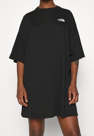 Schwarzes, oversized T-Shirt-Kleid aus weicher Baumwolle, mit Rundhalsausschnitt, kurzen Ärmeln und einem kleinen weißen Logo auf der linken Brust.