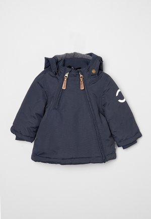 Veste bleu marine pour tout-petit avec capuche, deux fermetures éclair devant avec tirettes en cuir, et un demi-cercle blanc réfléchissant sur la manche gauche.