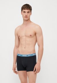 Fekete boxer alsónadrág világoskék Nike logós derékkal. Az anyag simának és testhezállónak tűnik, látható minták vagy díszítések nélkül.