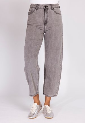 Gray high-waist wide-leg jeans worn with silver lace-up sneakers on a white background, cropped above the ankles.
