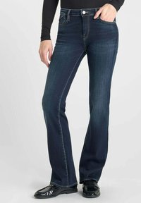 Jean évasé bleu foncé en denim avec cinq poches, une fermeture à bouton et des coutures contrastées le long des seams.