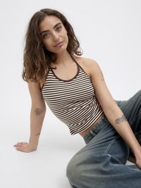 Hnedo-biele pruhované halter top s priliehavým strihom a ryhovanou textúrou. Kombinované s voľnými modrými džínsami. Jednoduché, čisté línie a ležérny štýl.