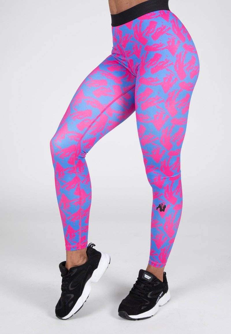 Rosa och blå mönstrade leggings med hög midja, tillverkade av ett elastiskt material, ihop med svarta sportskor.