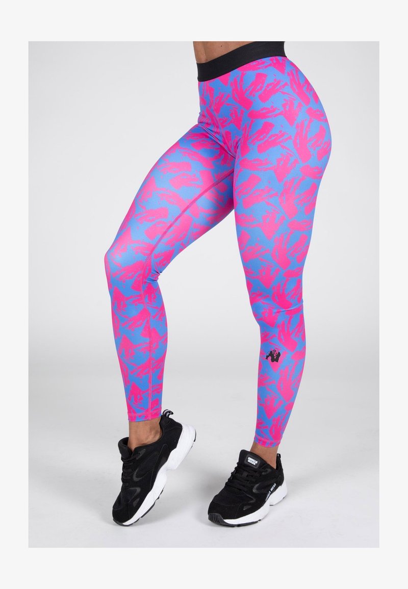 Roze en blauwe gestreepte leggings met een hoge tailleband, gemaakt van rekbaar materiaal, gecombineerd met zwarte sportschoenen.