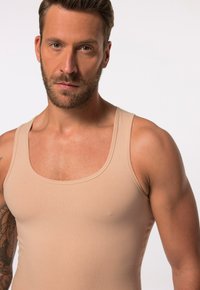 Top in beige realizzato in tessuto a coste, con scollatura a girocollo e spalline larghe, design aderente e texture liscia.