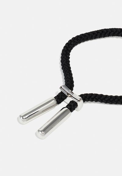 Un cordon tressé noir avec deux extrémités métalliques argentées brillantes et un fermoir argenté de connexion. Le cordon a une apparence texturée.