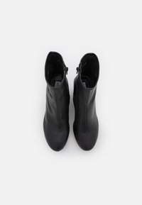 Black leather ankle boots with a smooth texture, slim profile, and side zippers. Features pointed toes and stitched detailing along seams.