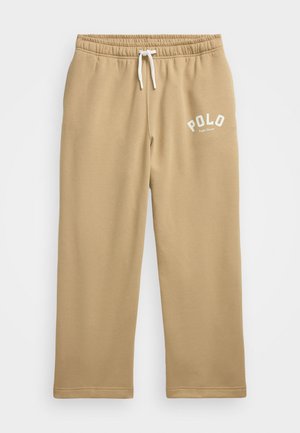Pantalons de survêtement beiges en matériau doux, dotés d'une taille élastique avec cordon de serrage et d'un logo "POLO" blanc imprimé en haut à gauche.