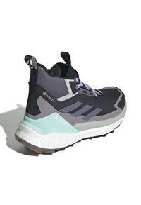 Svart og lilla tursko med polstret krage, forsterket tå, Gore-Tex-merke og en lys mintgrønn såle. Teksturert overdel med lisser.