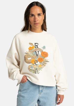 Sudadera de color crema con un corte relajado, que presenta un diseño gráfico colorido de flores y serpientes en el centro. Puños y cuello acanalados.