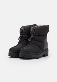 Botas puffer negras con parte superior acolchada, cuello de felpa y suela de goma. Presenta sutiles acentos de diseño en un color contrastante en el forro.