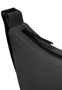 Borsa a tracolla nera realizzata in materiale liscio, con chiusura a zip, cuciture bianche a contrasto e una fascia larga per un trasporto confortevole.